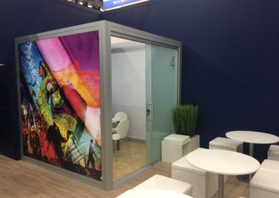 Quadro Vierkantprofile mit Glas Schiebetüren, Beiger Teppichboden, LED Posterboxleiste für Quadro Rahmen, PVC Bodenbelag, weiße Würfelhocker mit Beistelltisch Inox