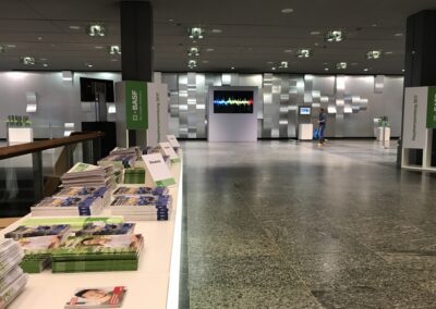 BASF Hauptversammlung, Eingangsbereich im Foyer mit beleuchteten Tischen für Bilanzbericht, Monitore auf Stelen