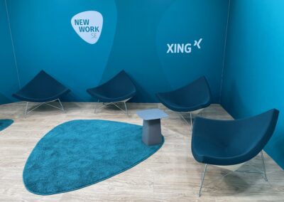 Interview Kulisse, Standard Messesystem OCTAwall mit blauen Wandgrafiken DEKOTEX Blockout, Stühle, Beistelltische ebenfalls blau, und blauer Hochfloorteppich in Logo-Emblem Form