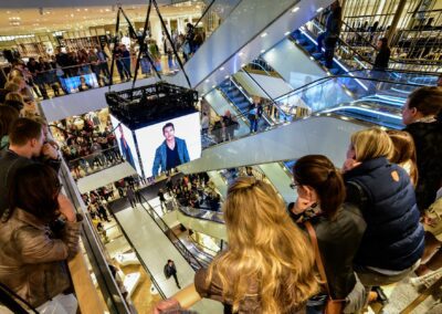 Modenschau Herrenmodenschau in einem Kaufhaus, Zuschauer stehen auf Rolltreppen, Zuschauer stehen auf allen Ebenen