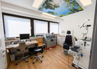 Lichtdurchfluteter Untersuchungsraum einer Arztpraxis mit medizinischen Geräten und Schreibtisch