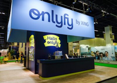 Dunkelblauer Raumbau mit umlaufender Theke auf dem onlyfy Messestand, darüber hängend die hellblaue Fernerkennung mit onlyfy by XING Logo
