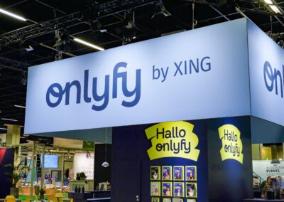 Hellblaue Fernerkennung mit onlyfy by XING Logo über dem auf dem Messestand befindlichen dunkelblauen Raumbau